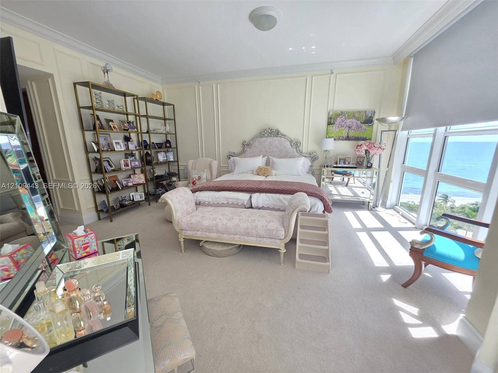 Floor-to-ceiling windows with coastal horizon, walls featuring custom crown molding and picture frame wainscoting, and carpeted flooring
