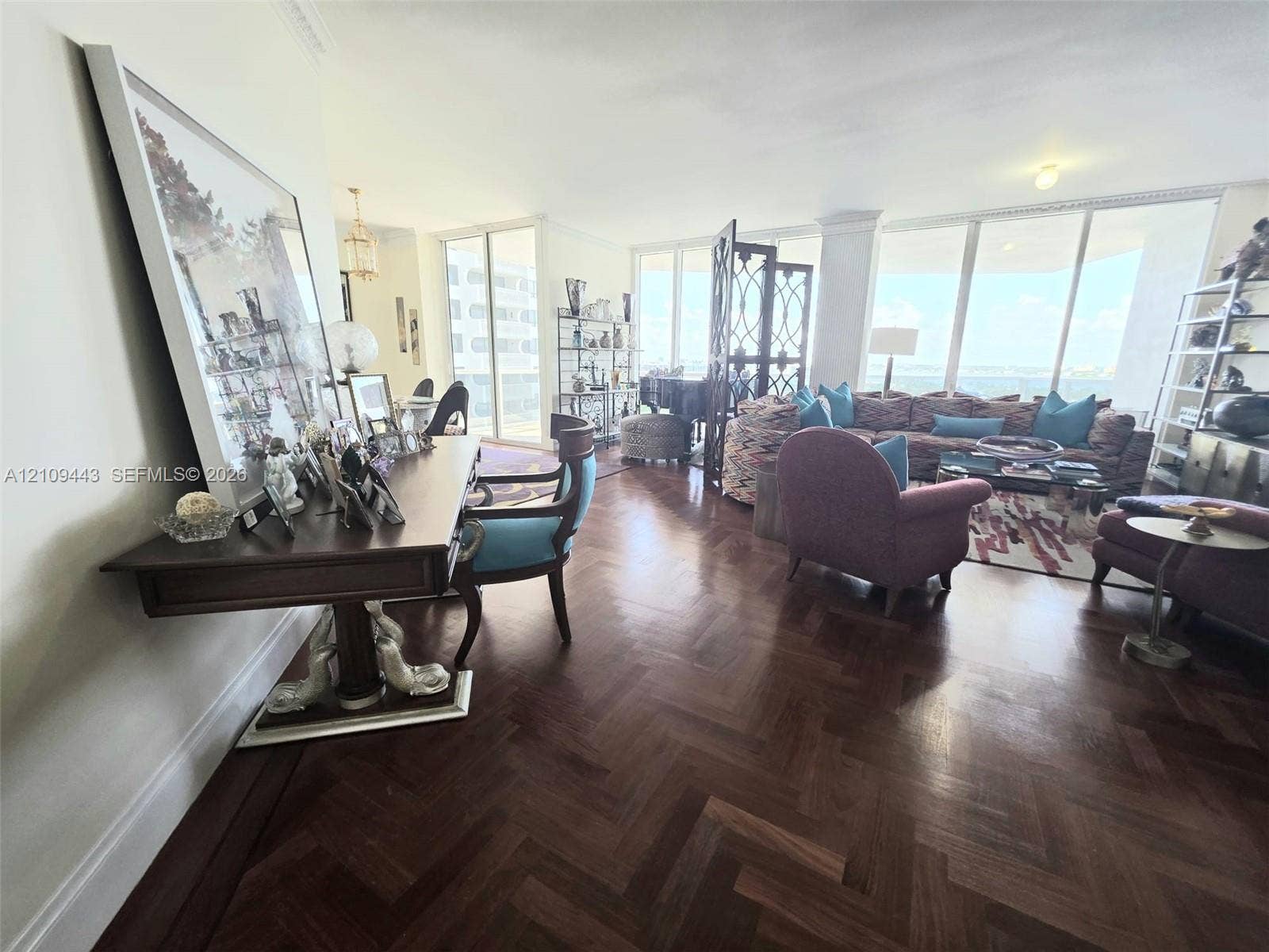 Herringbone-patterned wood-finish flooring, floor-to-ceiling windows, and crown molding