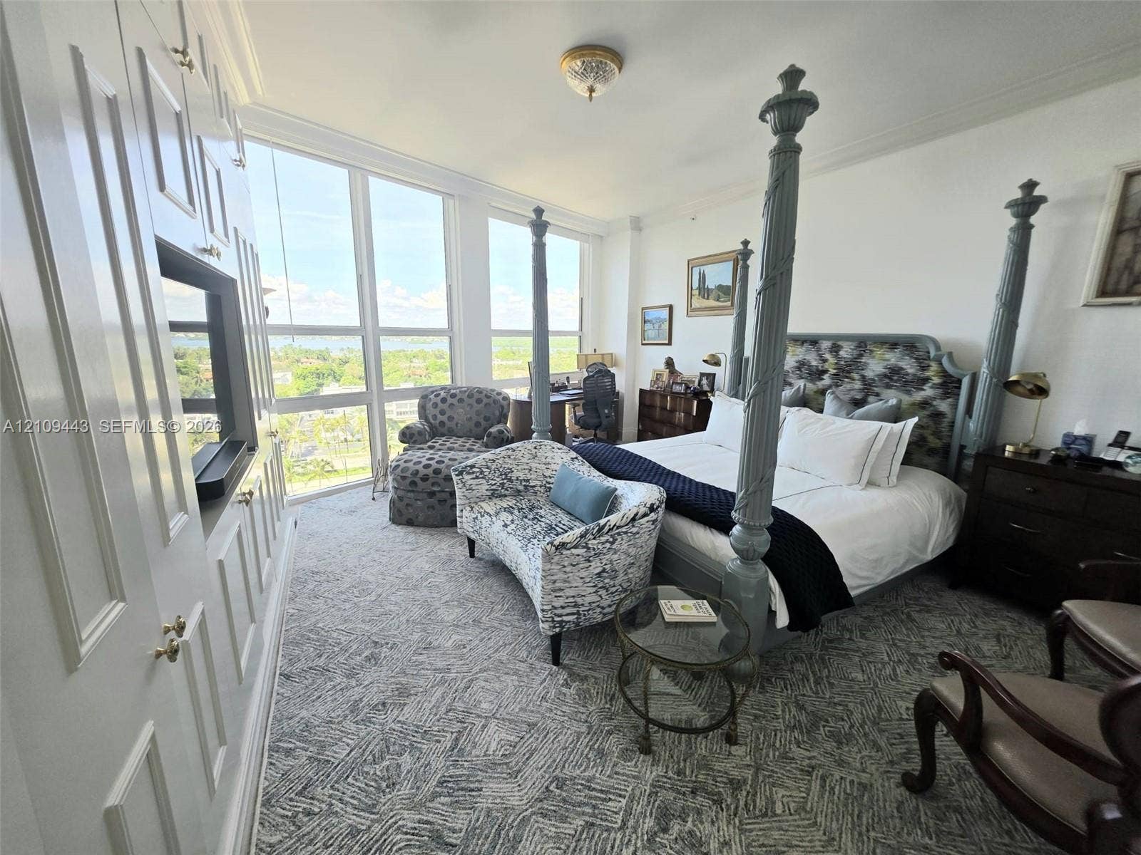 Floor-to-ceiling windows, built-in cabinetry with integrated shelving, and carpeted flooring
