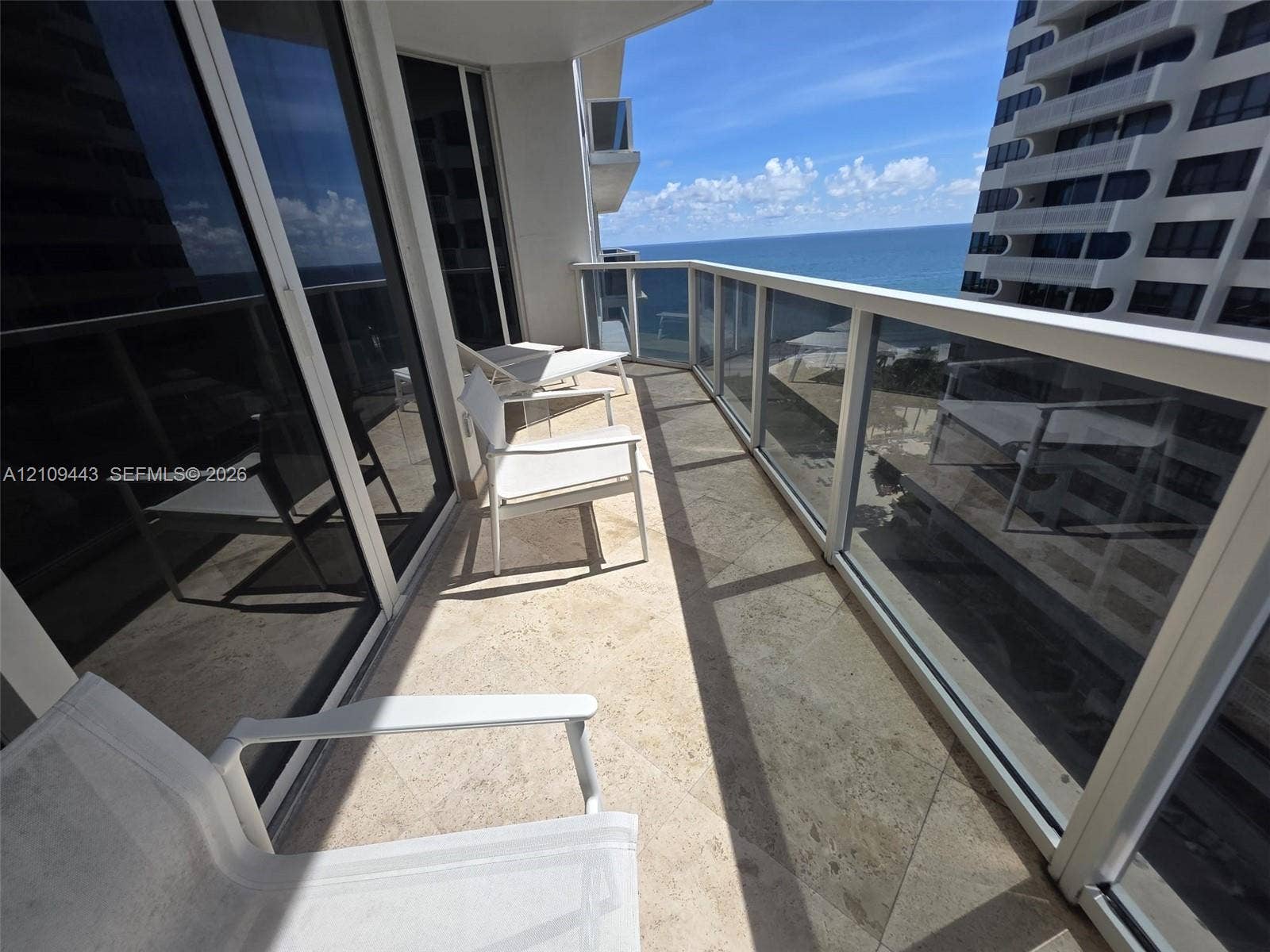 Covered balcony featuring stone flooring and a glass-paneled railing