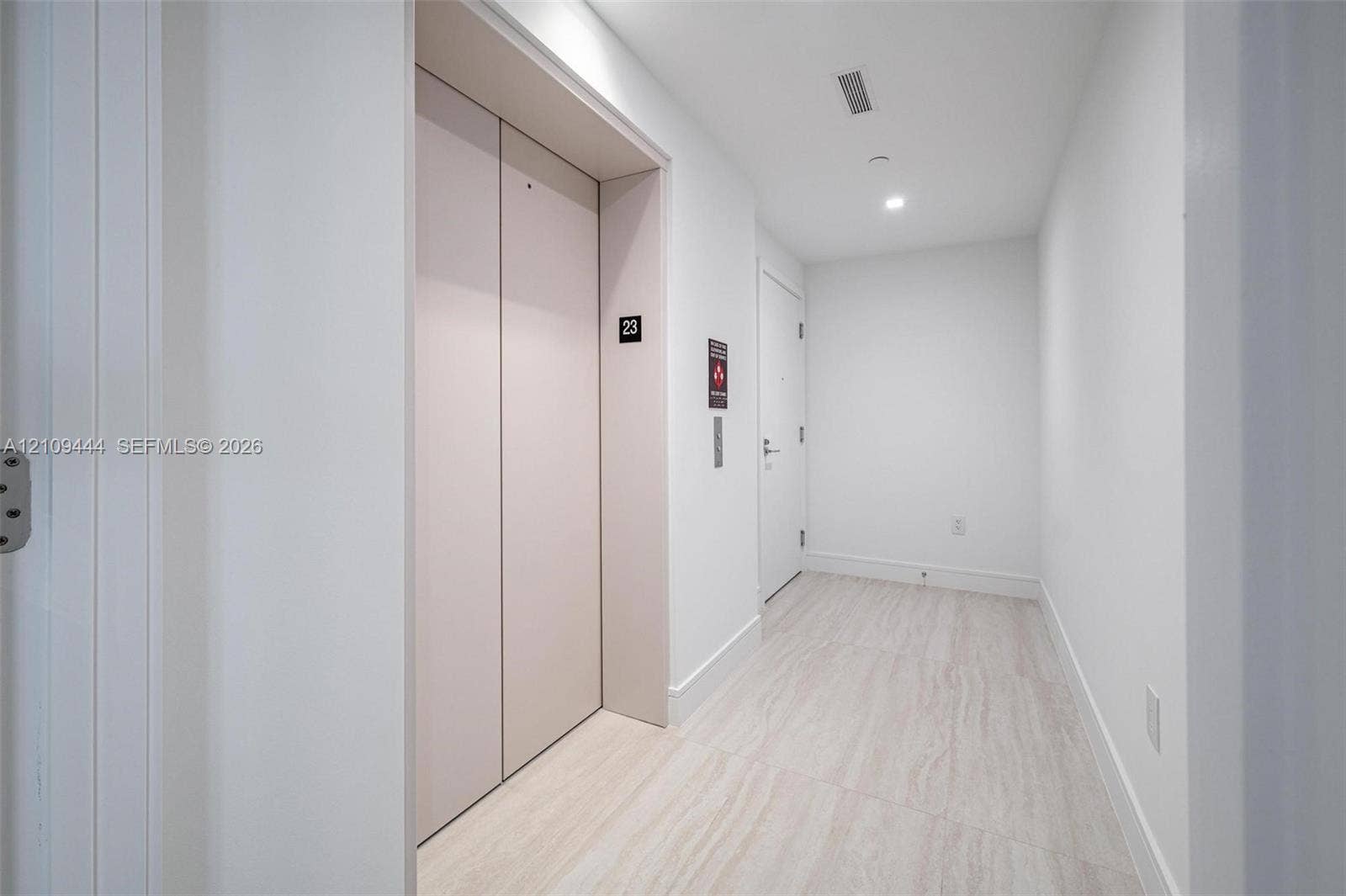 Private elevator access featuring matte-finish doors, recessed ceiling lighting, and large-format stone-look floor tiles