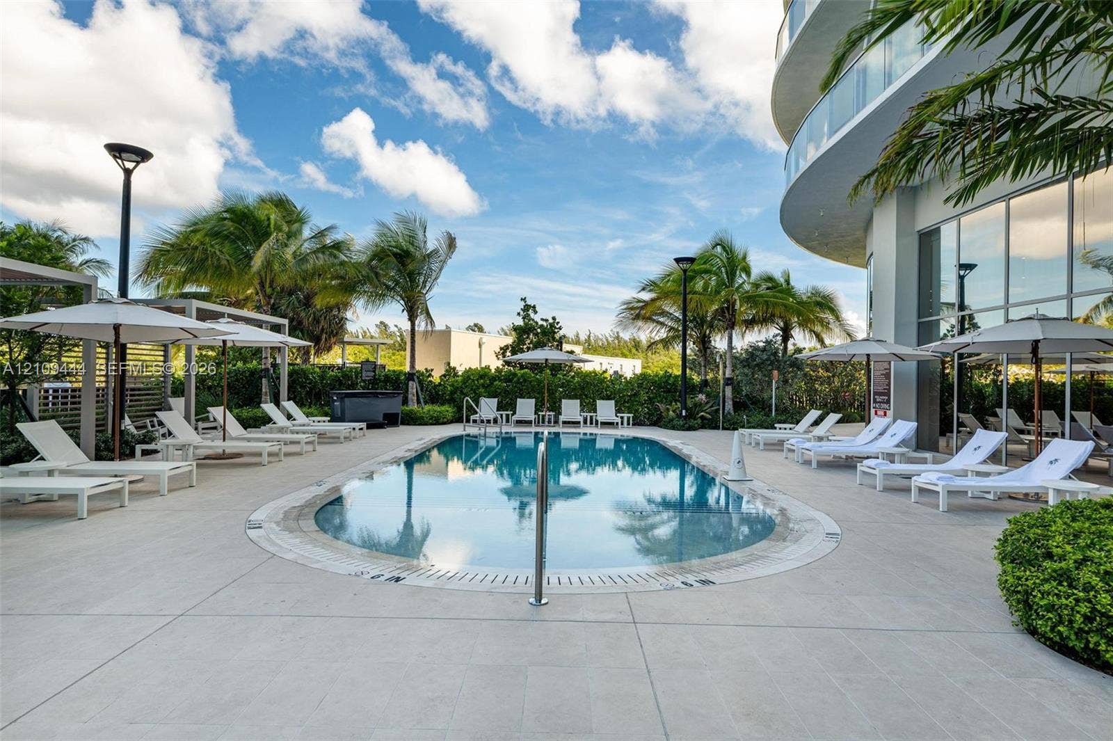 Swimming pool with concrete decking, perimeter landscaping, and floor-to-ceiling exterior glass facade