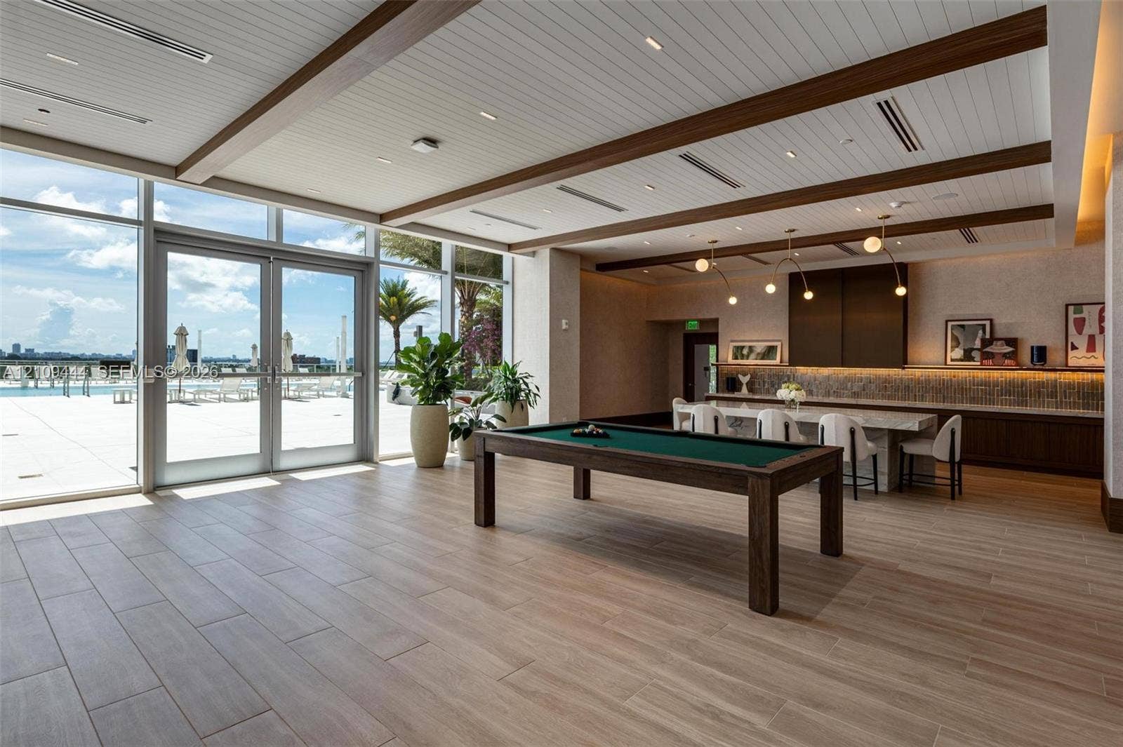 Expansive common area featuring wood-finish flooring, recessed lighting, and a coffered ceiling with exposed beams