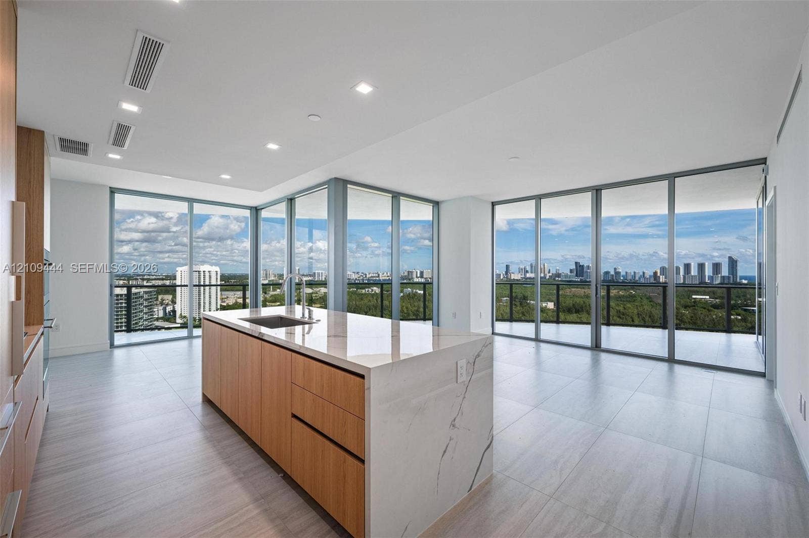 Kitchen featuring a center island with a stone-finish waterfall countertop, integrated cabinetry with wood-finish paneling, recessed lighting, and floor-to-ceiling glass panel walls