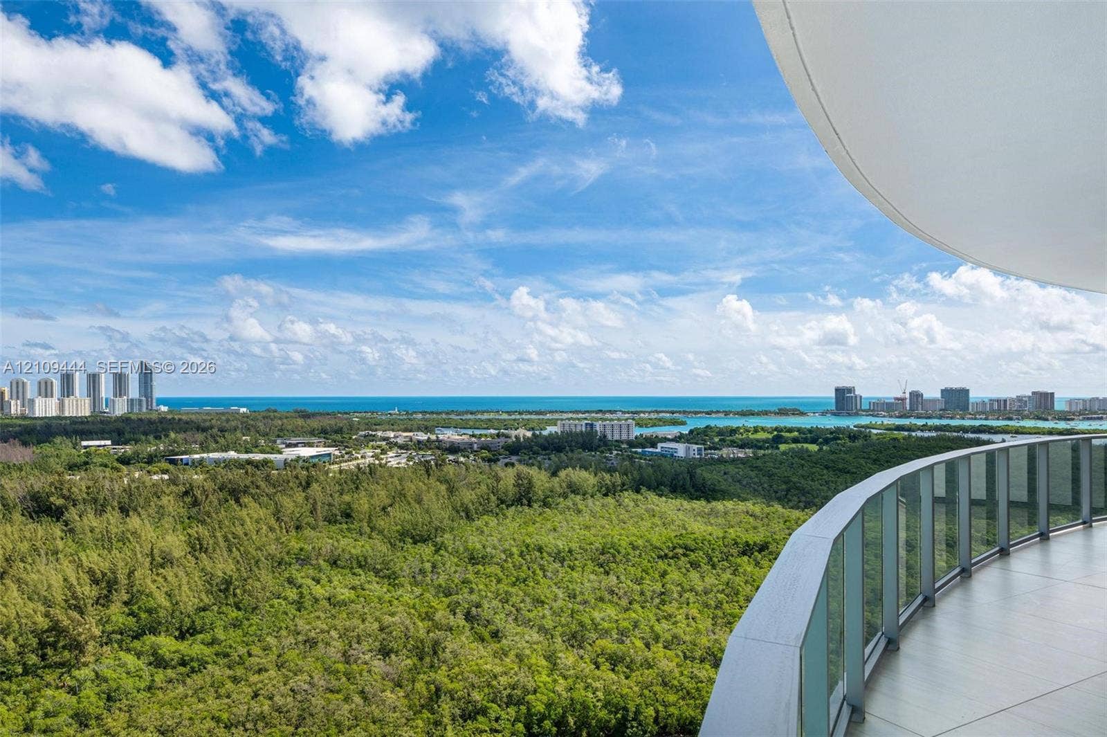 Curved balcony featuring tile flooring and a glass panel railing