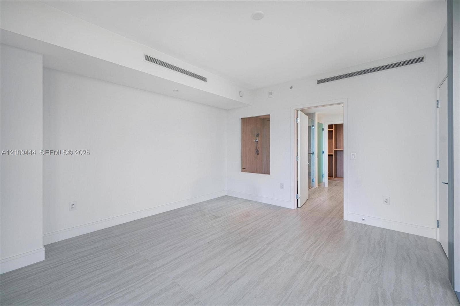 Neutral interior featuring wood-finish flooring, recessed ceiling linear diffusers, and a built-in recessed wall niche