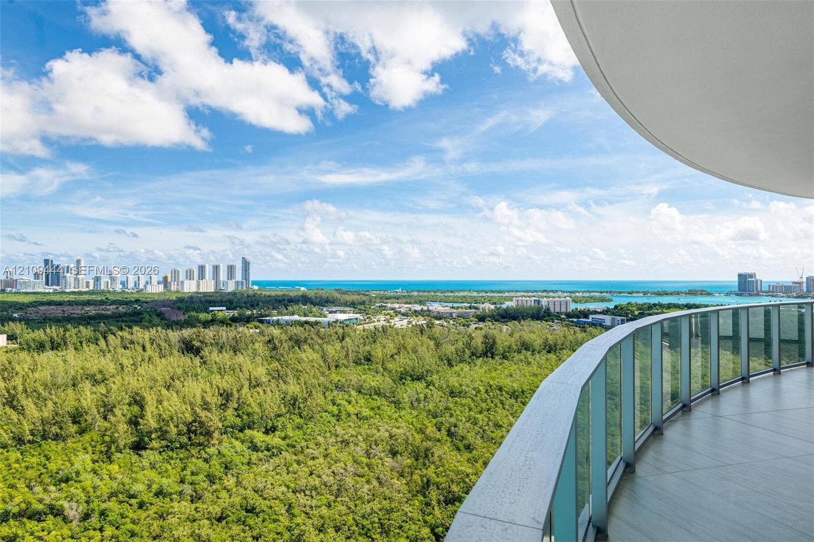 Curved balcony with tile flooring and a glass panel railing