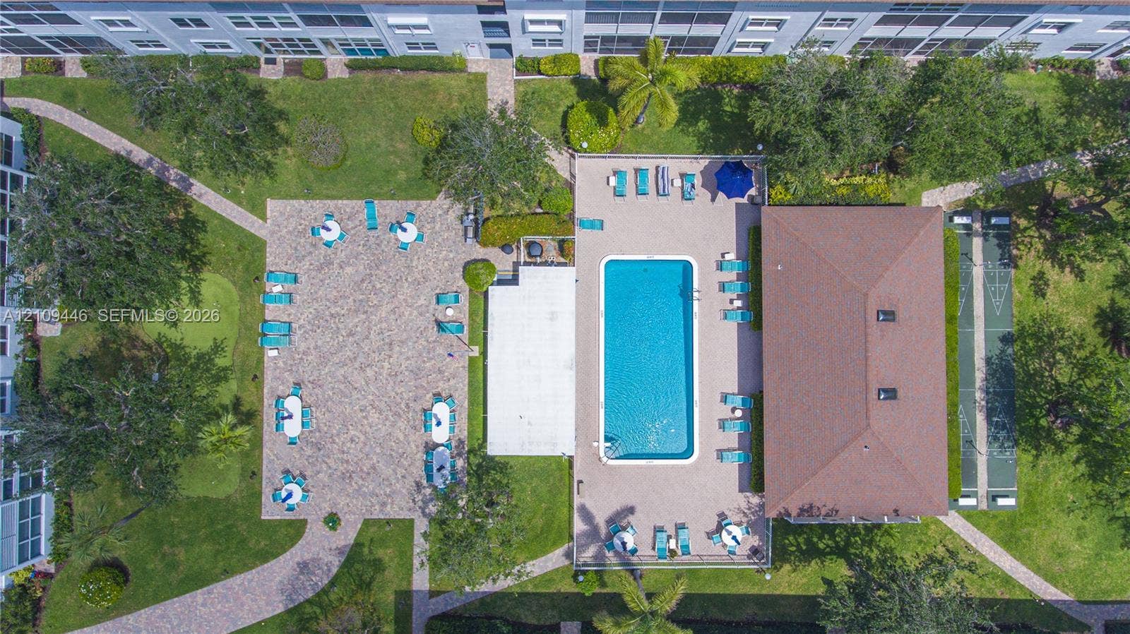 1501 S Ocean Boulevard, #117, Lauderdale-By-The-Sea, Lauderdale By The Sea, FL 33062 Outdoor recreation area featuring a rectangular swimming pool, paver deck, shuffleboard court, and manicured green space with mature landscaping