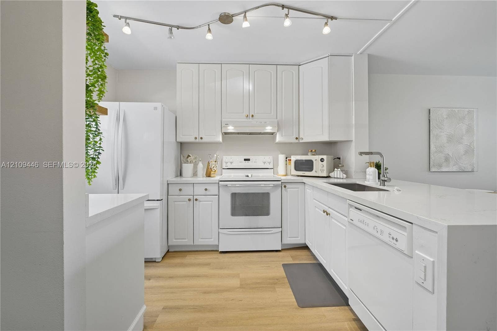 1501 S Ocean Boulevard, #117, Lauderdale-By-The-Sea, Lauderdale By The Sea, FL 33062 Kitchen featuring white cabinetry, solid-surface countertops, wood-finish flooring, and adjustable track lighting