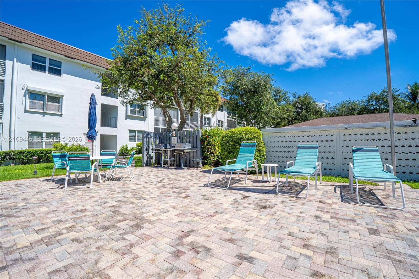 1501 S Ocean Boulevard, #117, Lauderdale-By-The-Sea, Lauderdale By The Sea, FL 33062 Outdoor patio featuring herringbone-patterned stone pavers, privacy screening, and built-in stainless steel grilling station