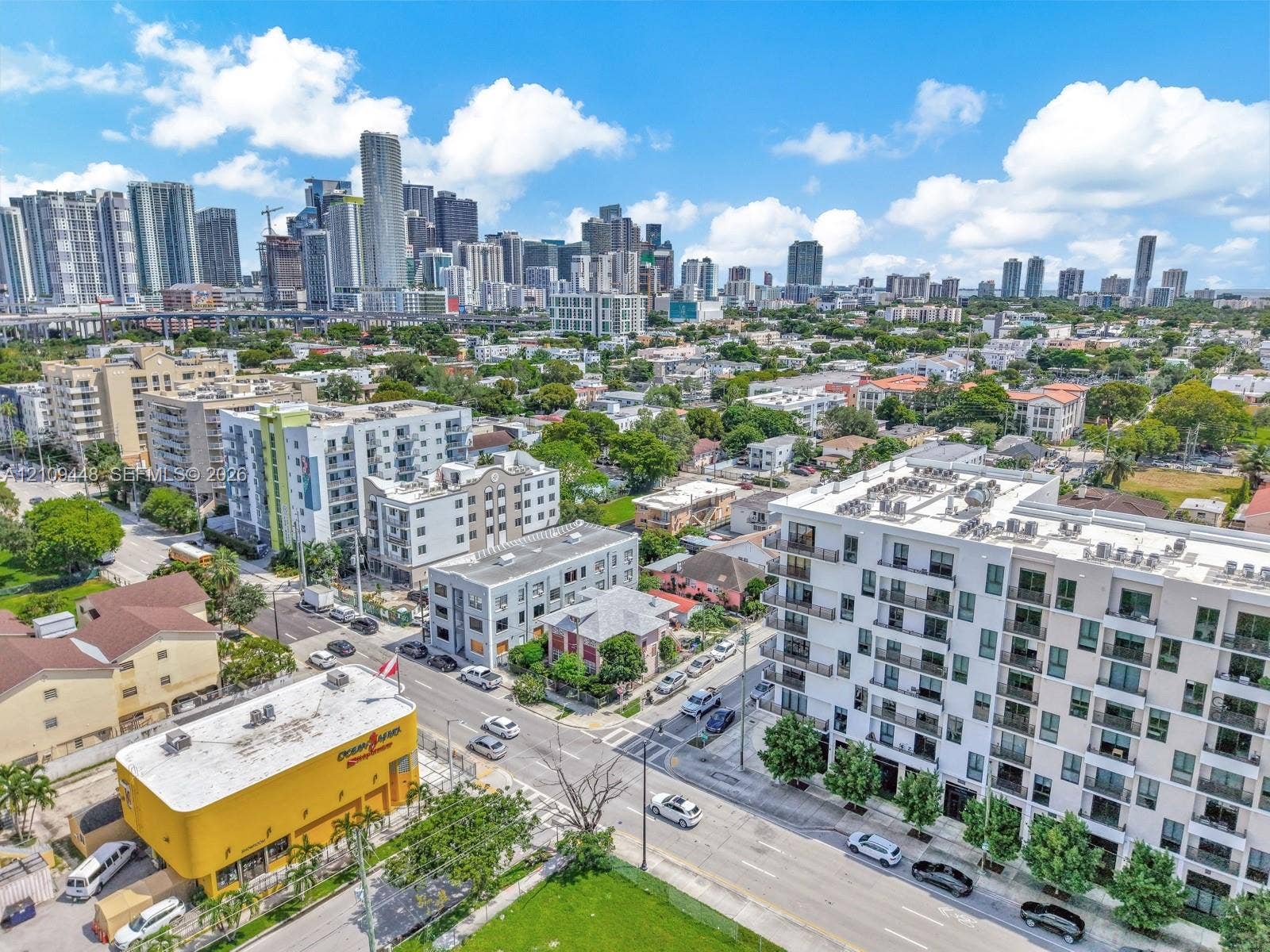 676 SW 1st Street, Miami, FL 33130 Aerial perspective of a multi-story residential building featuring private balconies, floor-to-ceiling windows, and a flat-roof design, set against a metropolitan skyline