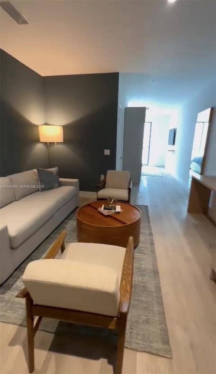 Interior space featuring light wood-finish flooring, a charcoal-toned accent wall, and a recessed ceiling lighting fixture
