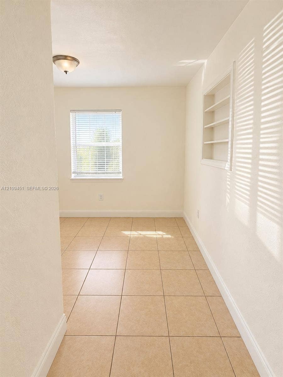 Room featuring neutral tile flooring, recessed wall shelving, and a semi-flush mount light fixture