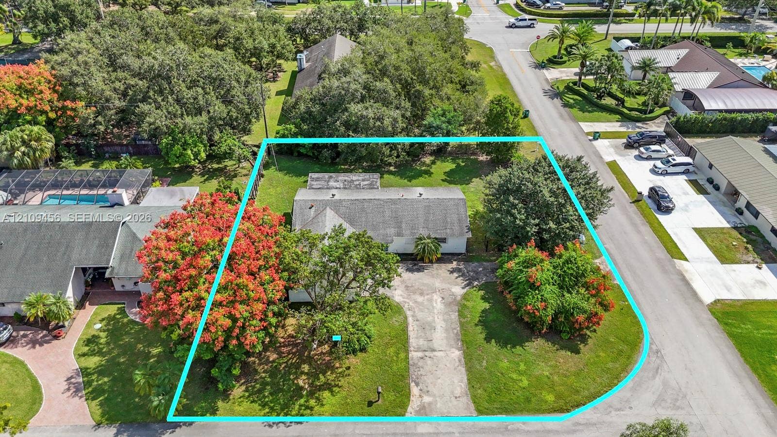 Corner lot featuring mature landscaping, expansive lawn, concrete driveway, and established tree canopy