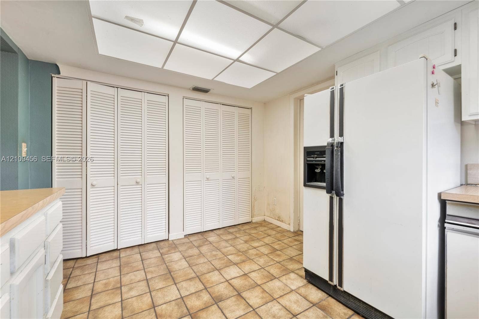 Kitchen area featuring ceramic tile flooring, built-in floor-to-ceiling louvered-door cabinetry, and an integrated ceiling light panel