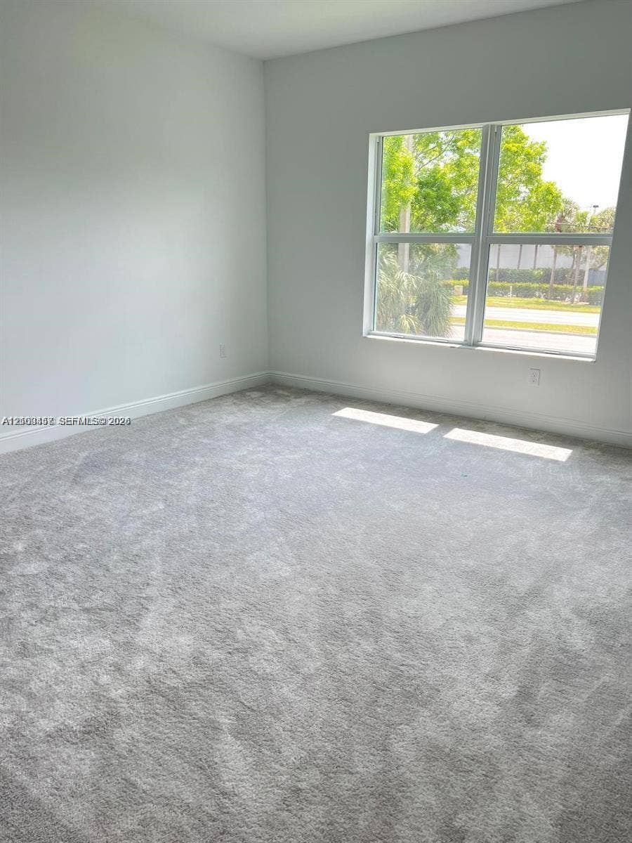 Neutral interior space featuring wall-to-wall carpeting and a large multi-pane window