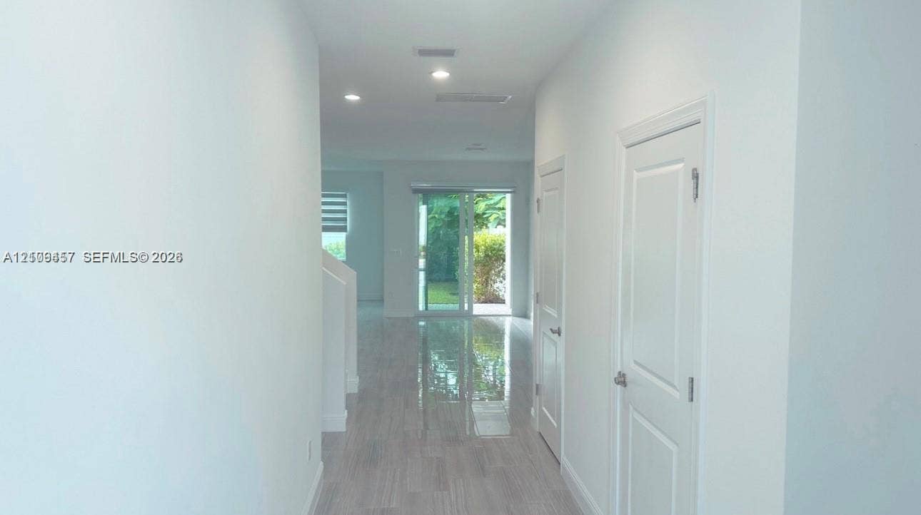 Interior hallway featuring light-toned wood-finish flooring, recessed lighting, and sliding glass doors