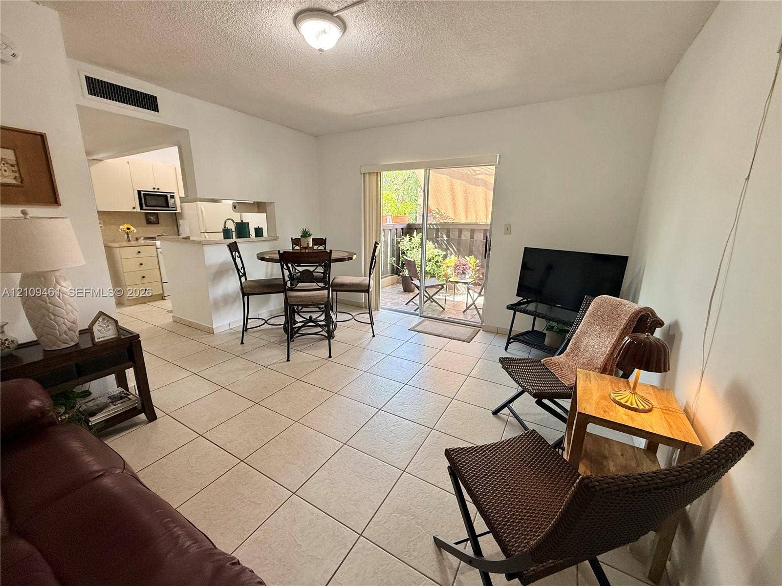 10776 N Kendall Drive, #F11, Miami, FL 33176 Ceramic tile flooring, pass-through kitchen window with breakfast bar, and sliding glass door with exterior patio access