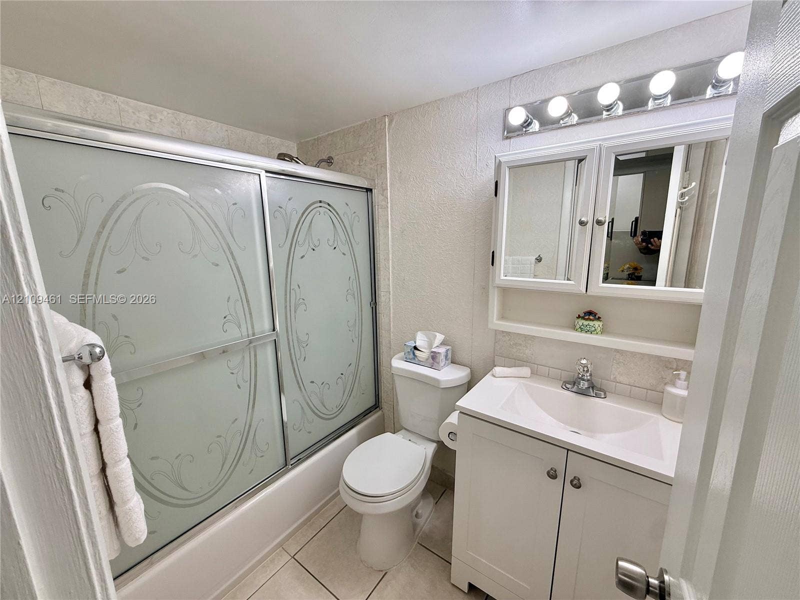 10776 N Kendall Drive, #F11, Miami, FL 33176 Bathroom featuring a tub-shower combination with etched glass sliding doors, a white vanity cabinet with an integrated sink, a multi-bulb vanity light fixture, and tile flooring