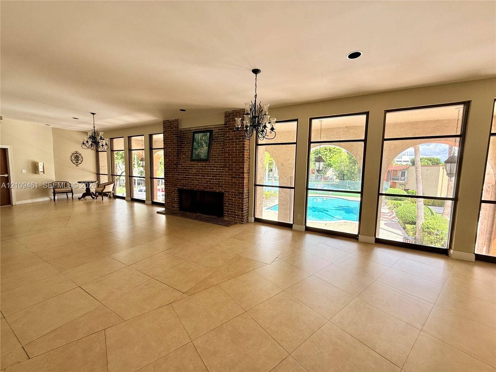 10776 N Kendall Drive, #F11, Miami, FL 33176 Large-format tile flooring, brick fireplace, and floor-to-ceiling windows with exterior pool access
