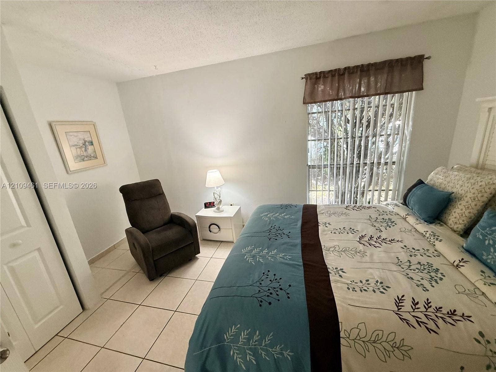 10776 N Kendall Drive, #F11, Miami, FL 33176 Neutral-toned ceramic tile flooring, multi-panel door with brass-finish hardware, and large sliding window with vertical blinds