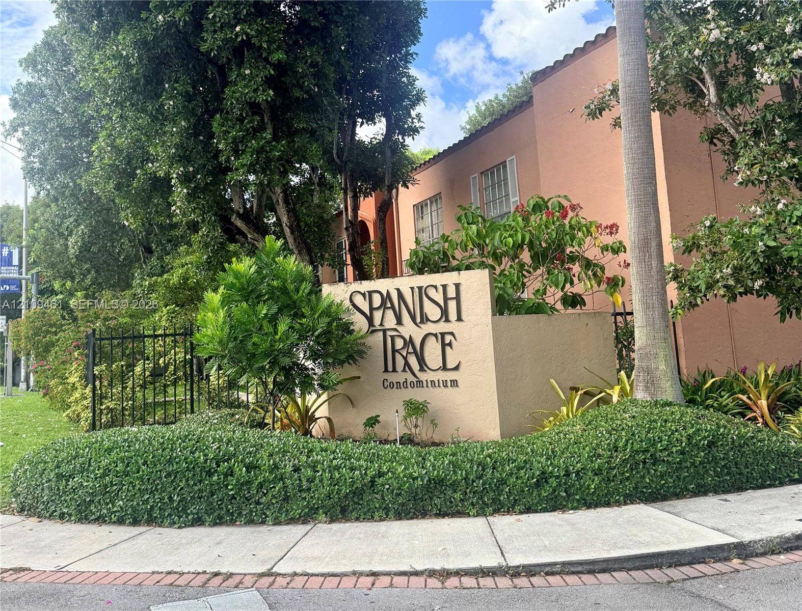 10776 N Kendall Drive, #F11, Miami, FL 33176 Stucco monument signage featuring professional lettering, complemented by mature landscaping, palm trees, and a decorative black iron perimeter fence