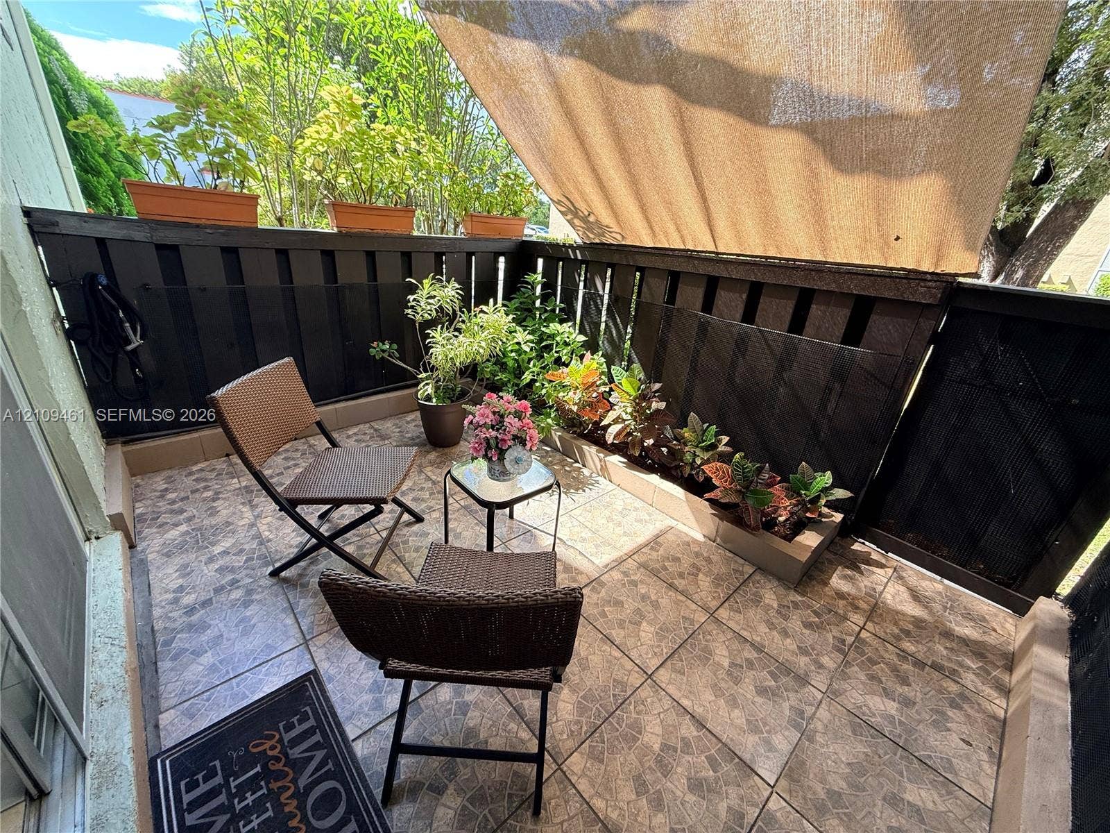 10776 N Kendall Drive, #F11, Miami, FL 33176 Private balcony featuring tiled flooring, built-in wooden perimeter privacy fencing, and a retractable fabric awning