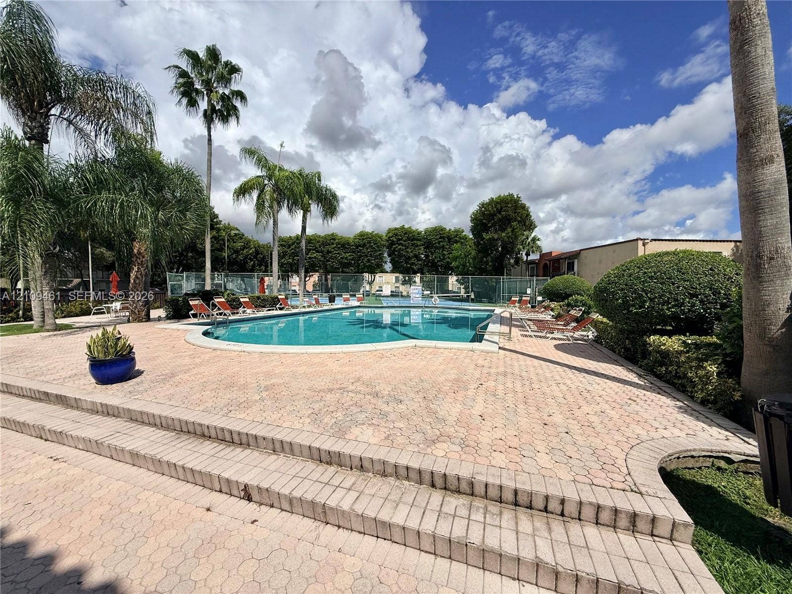 10776 N Kendall Drive, #F11, Miami, FL 33176 In-ground swimming pool featuring paver decking, multi-level stairs, and mature palm trees