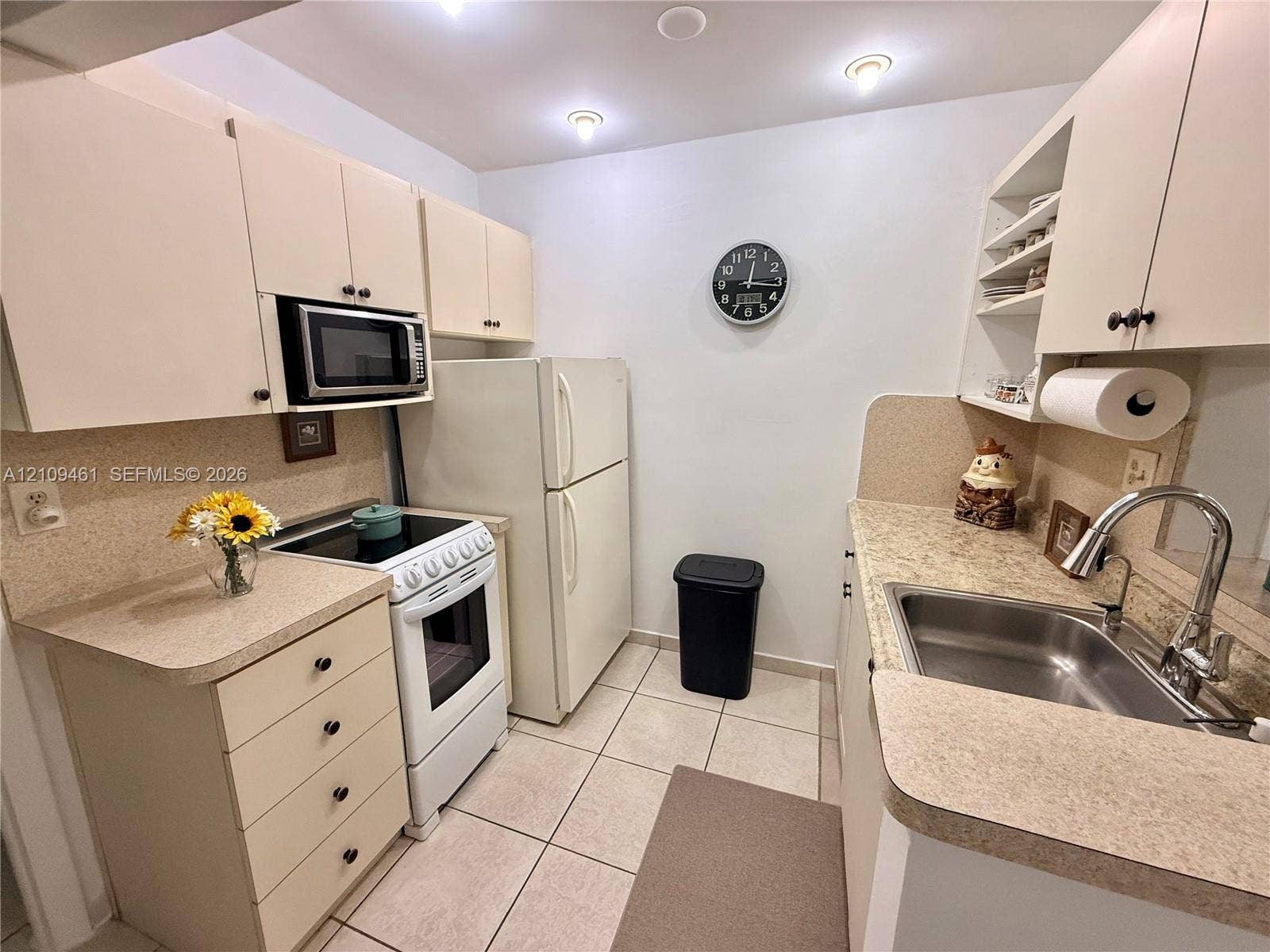 10776 N Kendall Drive, #F11, Miami, FL 33176 Kitchen featuring cabinetry with integrated storage, solid-surface countertops, stainless steel sink with high-arc faucet, and tiled flooring