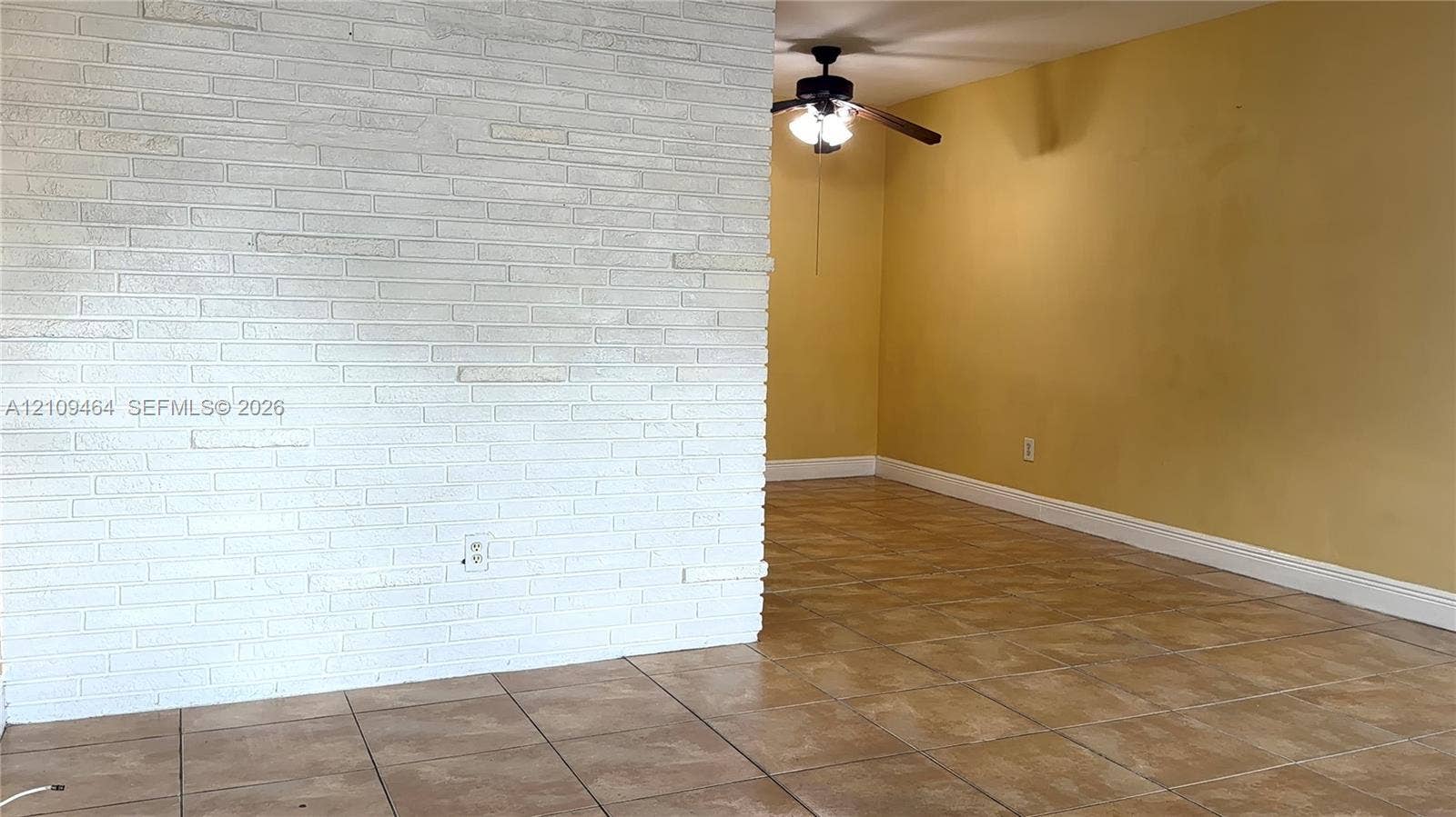 White painted masonry accent wall, neutral ceramic tile flooring, and ceiling-mounted light fixture