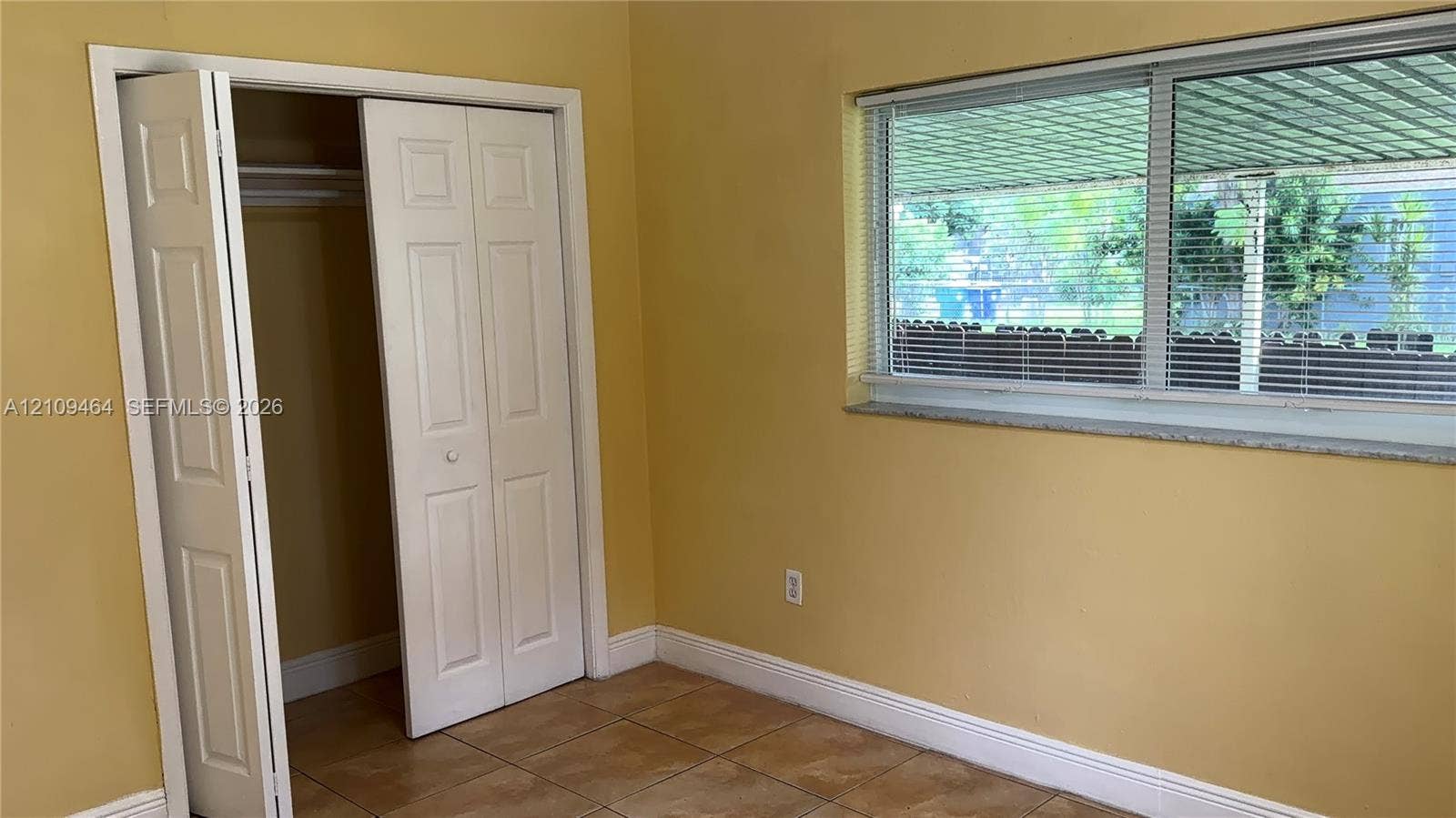 Room featuring large-format ceramic tile flooring, a horizontal sliding window with a stone sill, and a closet with bifold doors