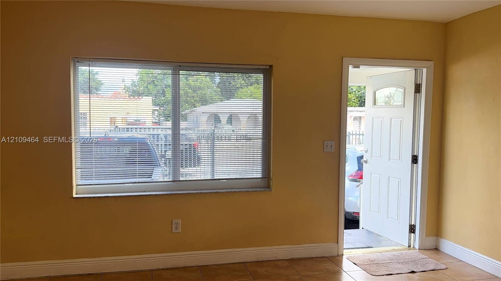 Large dual-pane sliding window, exterior door with inset glass panel, and neutral tile flooring