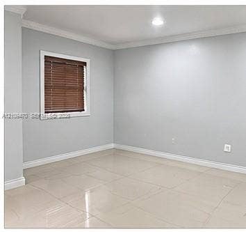 Neutral-toned interior space featuring light-colored tile flooring, crown molding, and recessed lighting