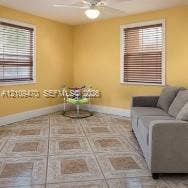 Interior space featuring ceramic tile flooring, two windows with horizontal blinds, and a white ceiling fan with integrated lighting