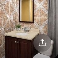 Dark-finish vanity cabinet, solid-surface countertop with integrated oval basin, polished chrome faucet, framed mirror, and decorative wall tiling