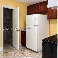 Dark-toned cabinetry, white refrigerator, black range, and patterned stone-style flooring