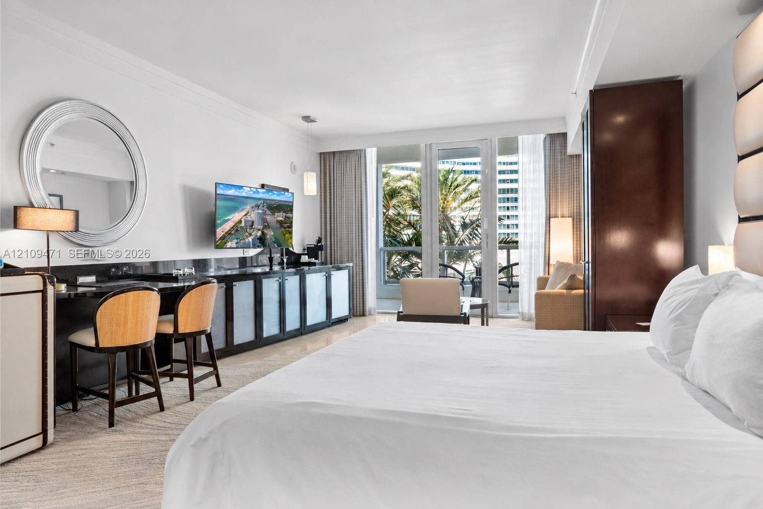 Custom built-in cabinetry with stone-finish surfaces, circular wall mirror, integrated lighting, and glass-paneled exterior door