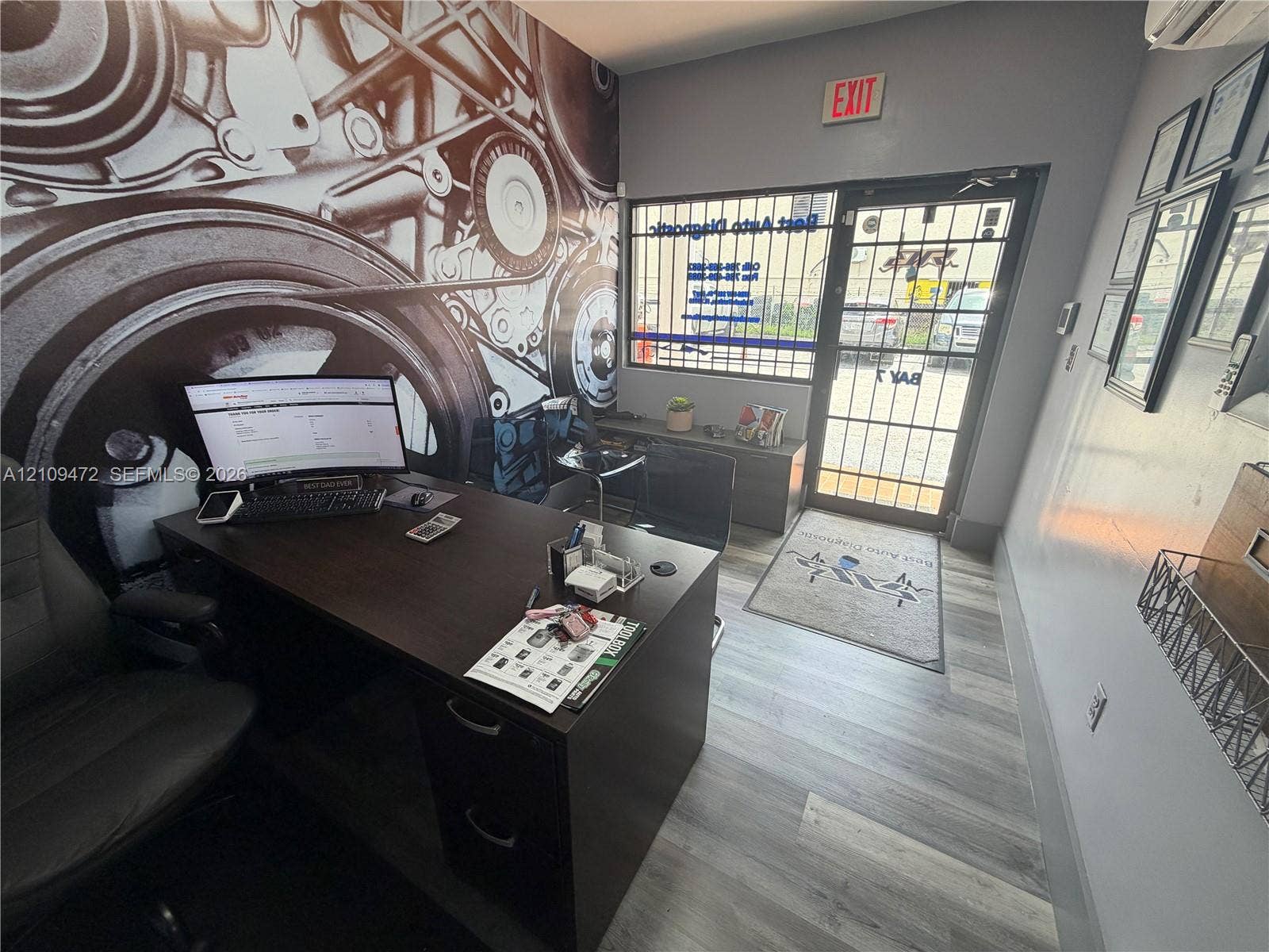 Office space featuring wood-finish flooring, a glass-panel entry door with integrated metal security grilles, and a large-format mural wall treatment