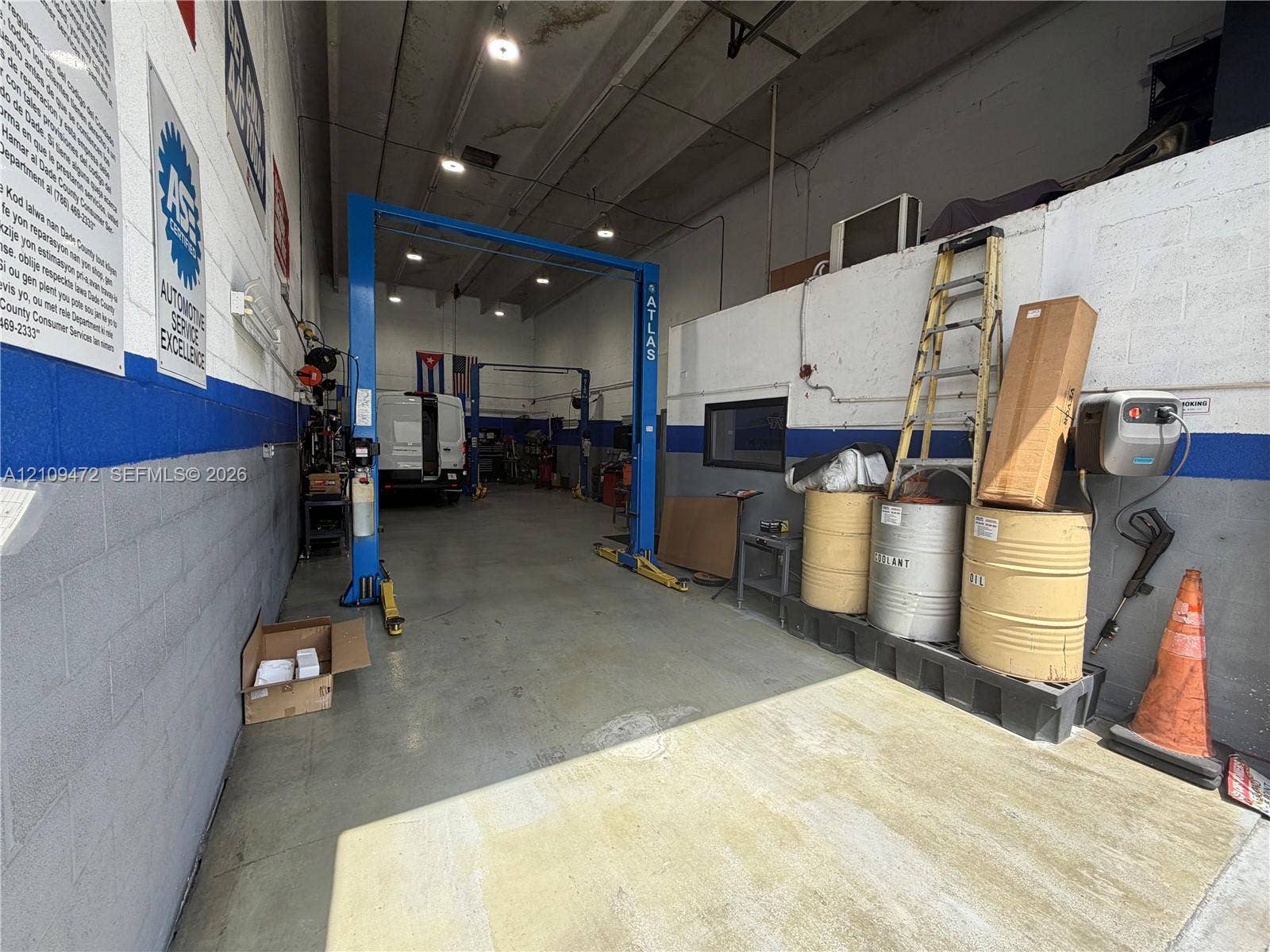 Commercial bay featuring high ceilings, concrete flooring, recessed lighting, and a two-post automotive lift