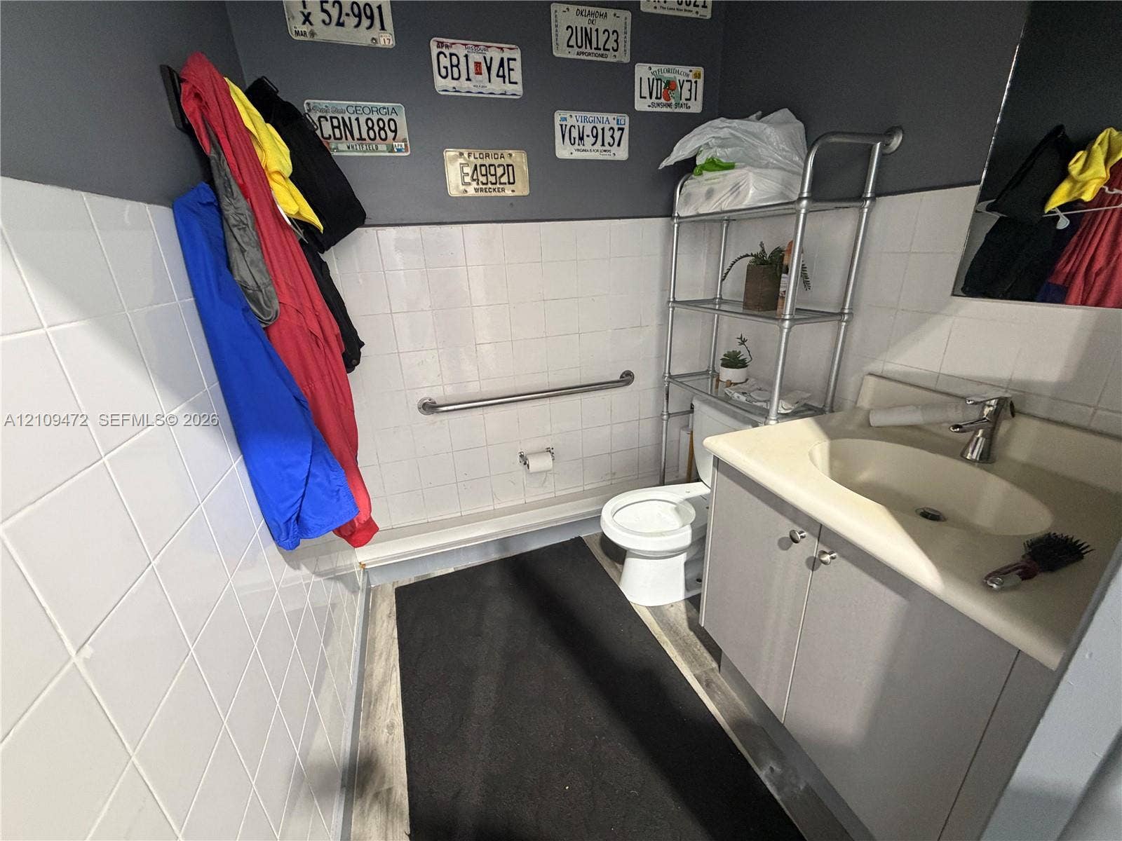 Vanity featuring a molded sink basin and gray cabinetry, white wall tile, horizontal grab bar, and wood-finish flooring