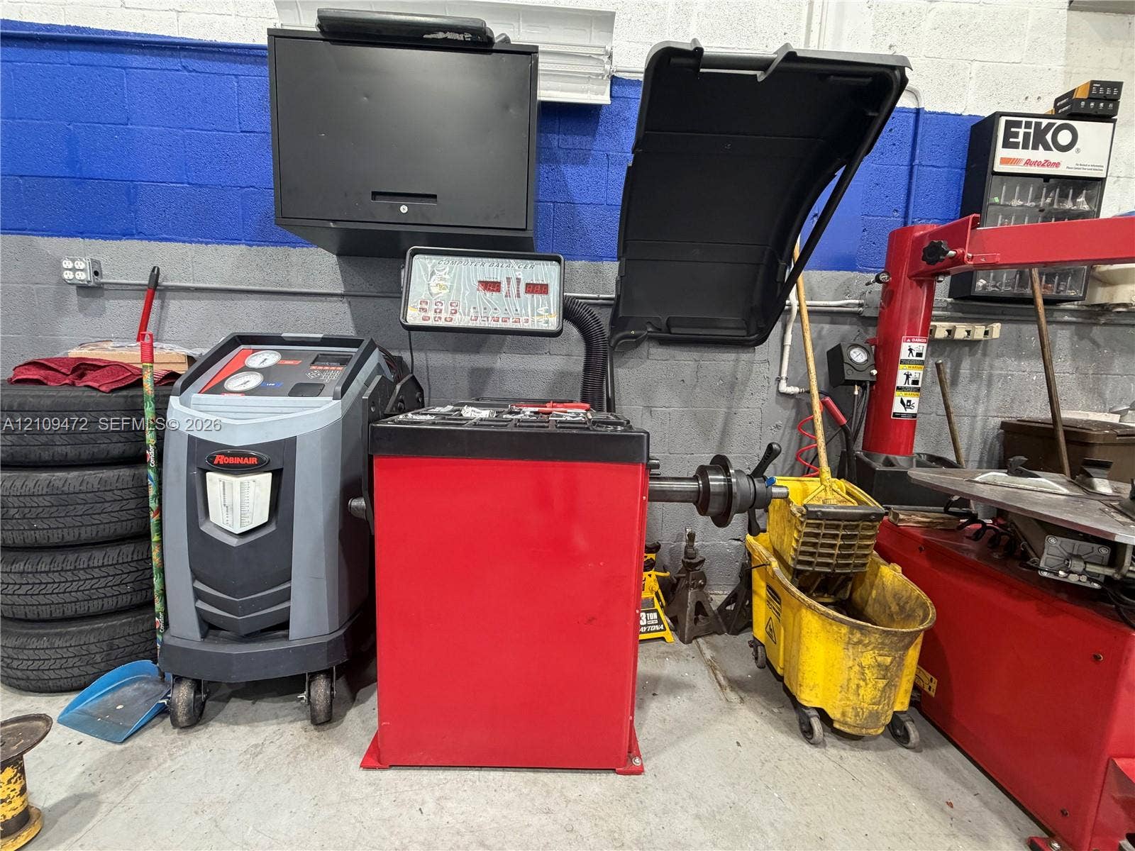 Professional-grade automotive equipment featuring a digital tire balancer with red steel casing, a wheel service machine, and mounted diagnostic console