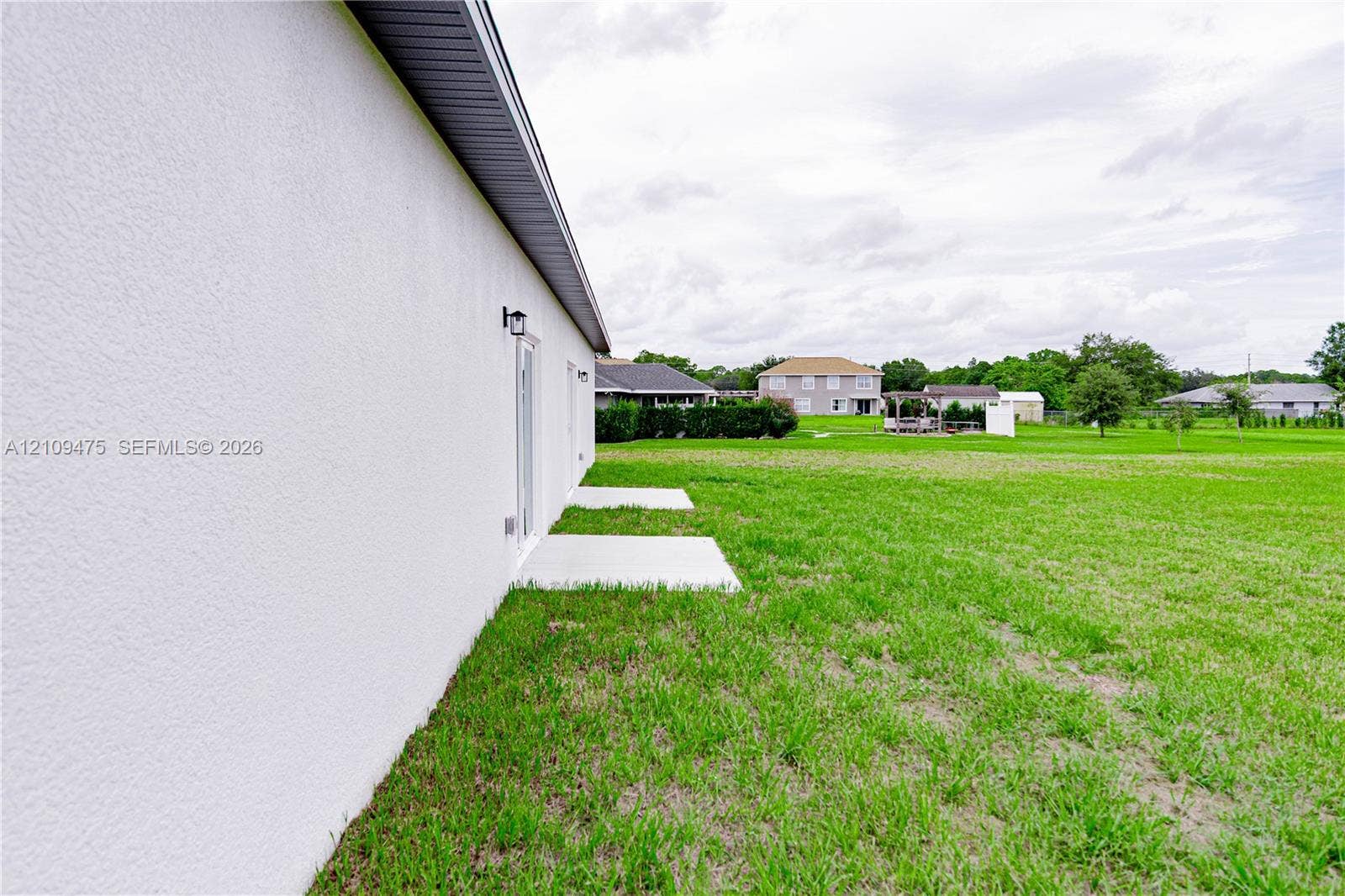 Stucco exterior finish with concrete patio slabs and mounted outdoor light fixtures