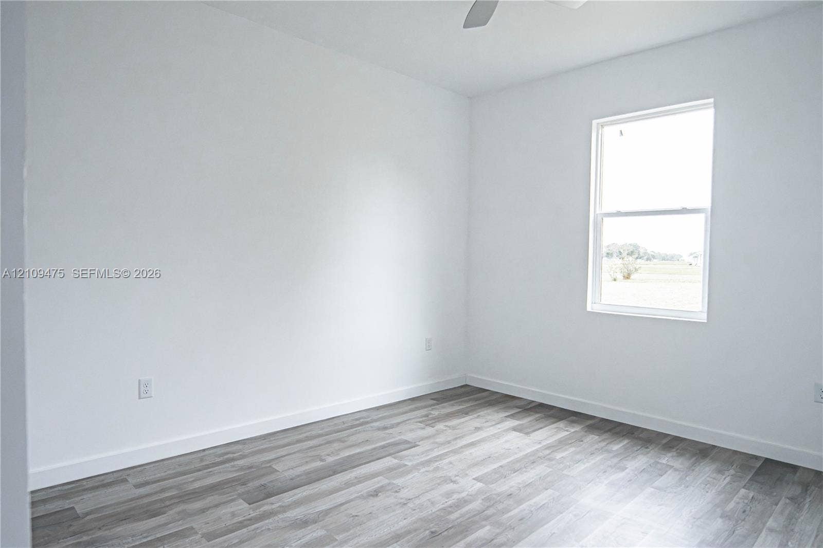 Room with neutral walls, wood-finish flooring, single-hung window, and overhead ceiling fan
