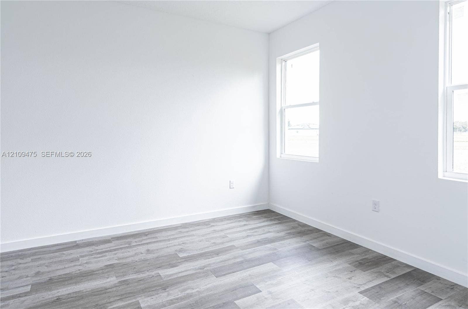 Neutral-toned interior space featuring wood-finish flooring and dual double-hung windows