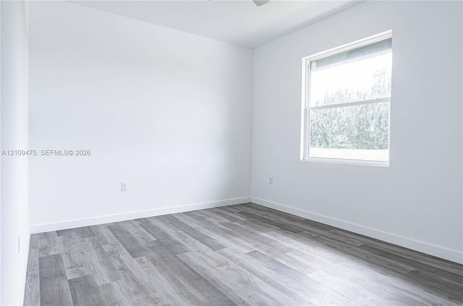 Interior space featuring wood-finish flooring, white walls, and a single-pane window