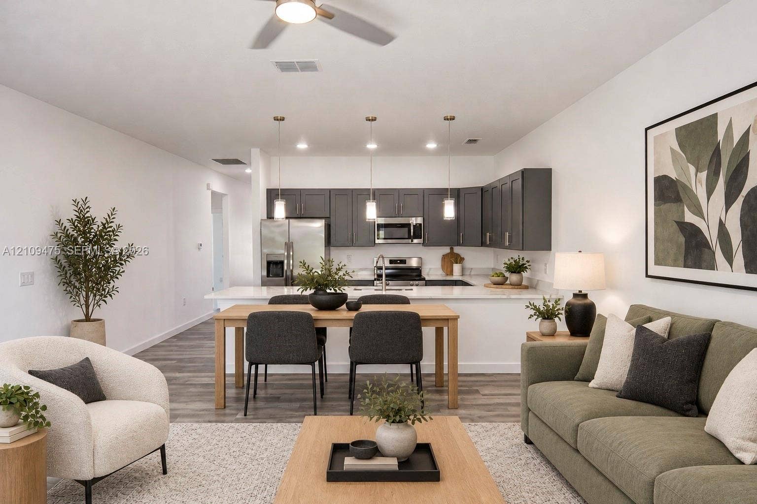 Kitchen featuring dark cabinetry, quartz countertops, stainless steel appliances, a peninsula, and wood-finish flooring
