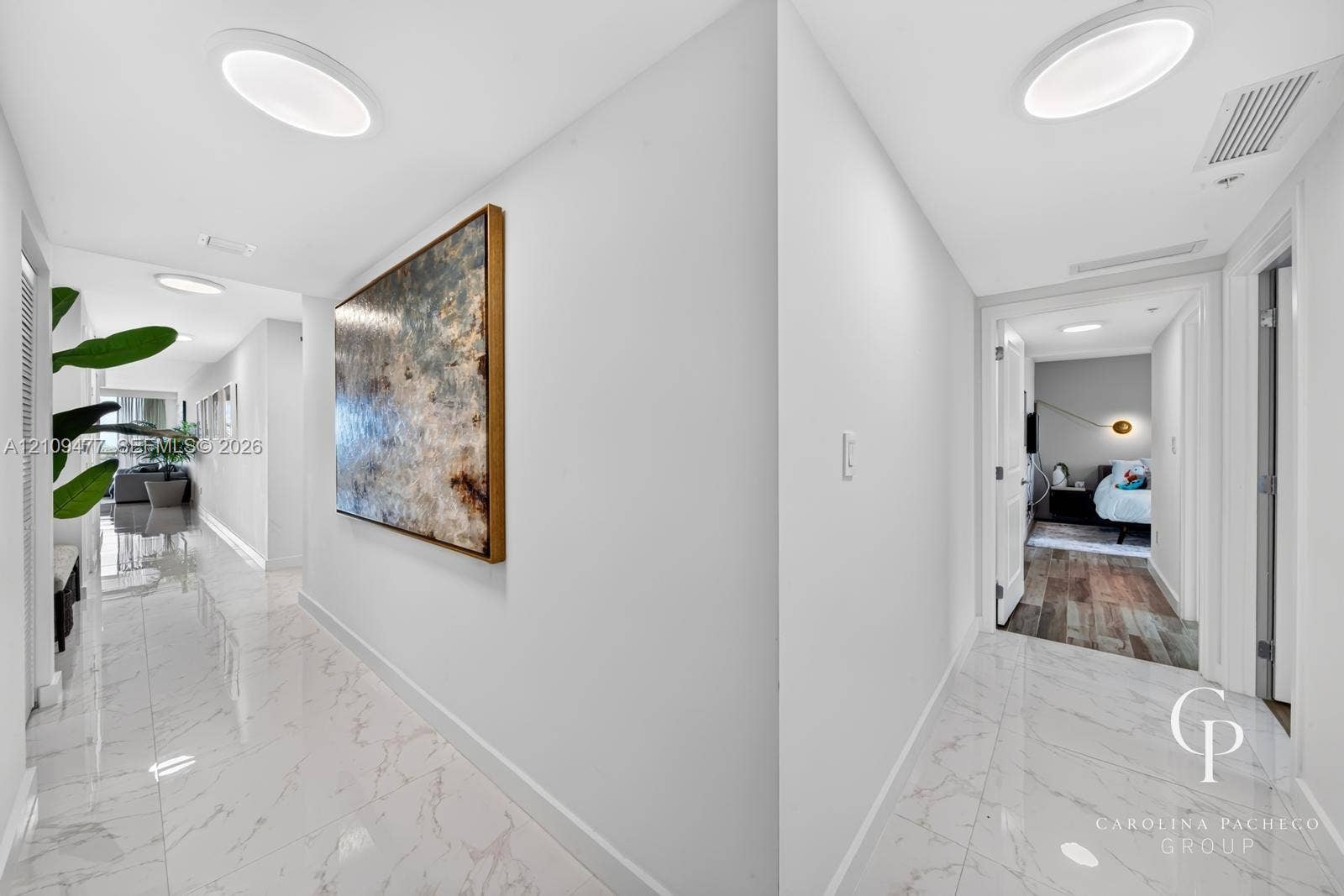 Hallway featuring polished stone-finish tile flooring, recessed LED ceiling lighting, and crisp white wall finishes