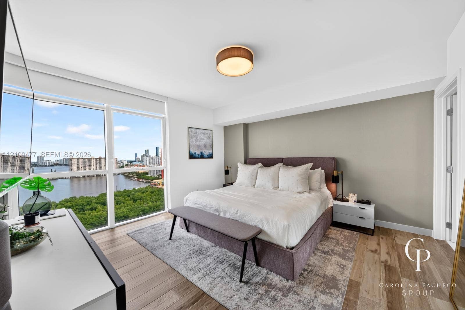 Floor-to-ceiling windows, wood-finish flooring, accent wall, and flush-mount ceiling lighting