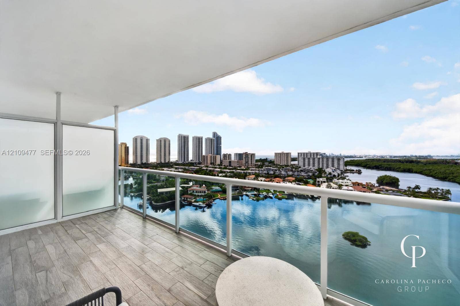 Covered balcony featuring wood-finish tile flooring, glass panel railing, and frosted privacy screens