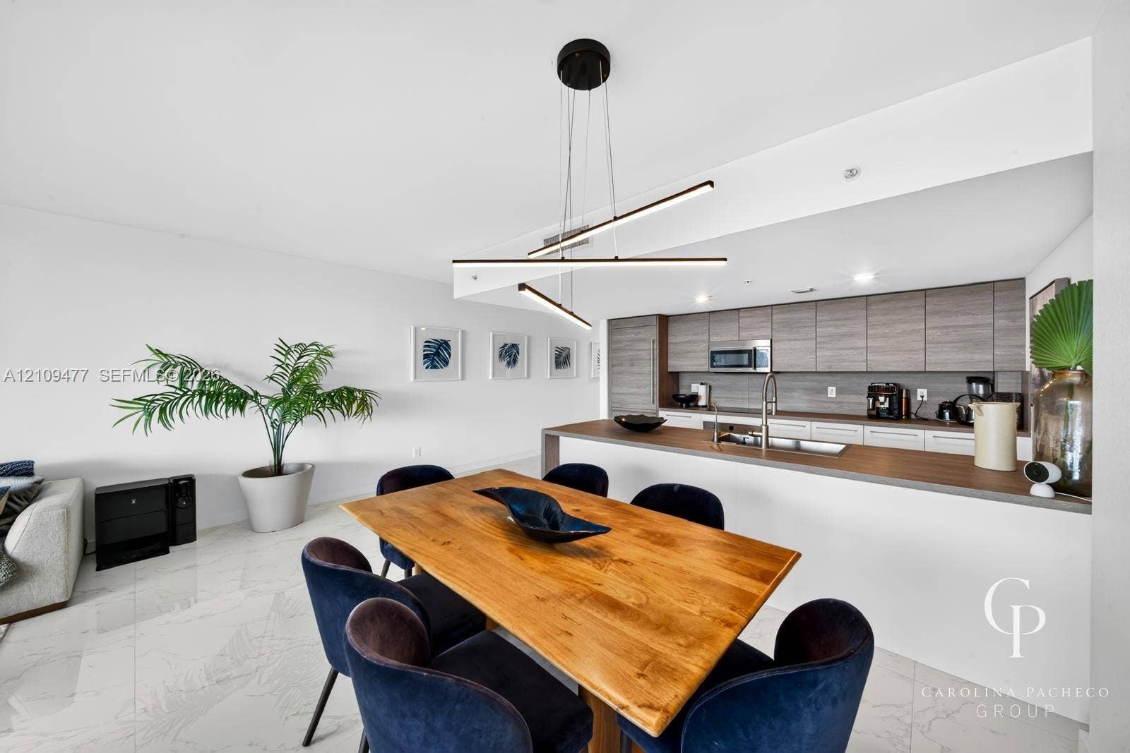 Modern kitchen featuring horizontal-grain wood cabinetry, integrated stainless steel appliances, and a peninsula with a composite countertop